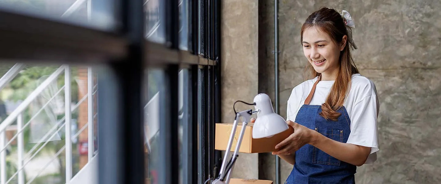A young woman unpacks boxes as she furnishes her new business office