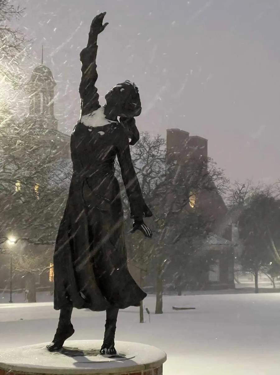The 'She Gave Us Wings' statue on the Denton campus coated with snow as more snow falls around it.
