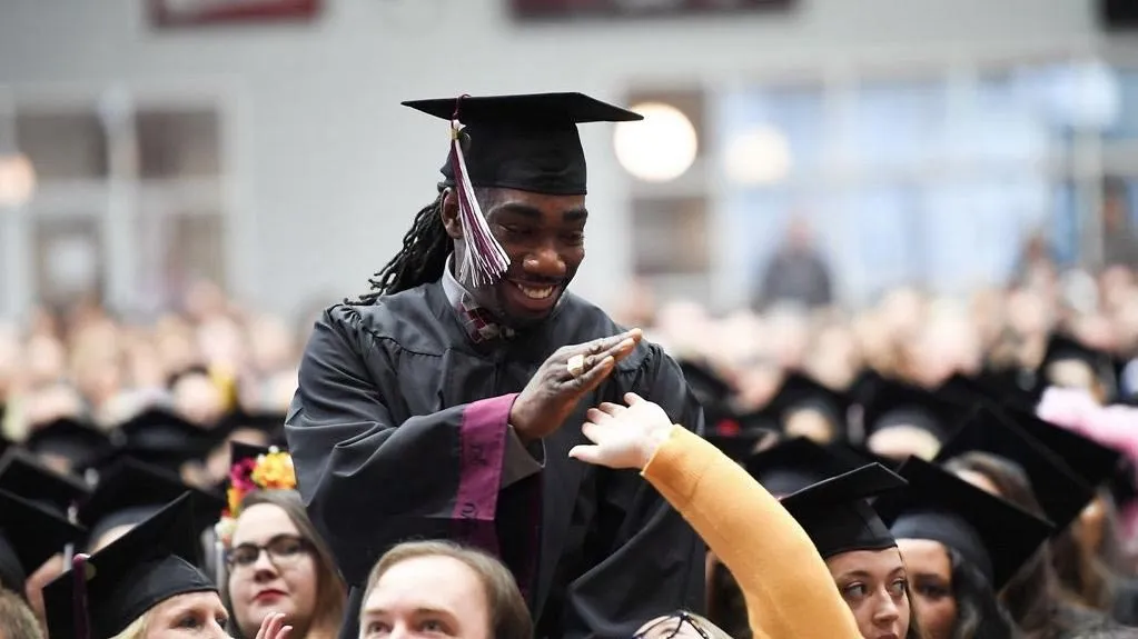 New graduate Ryan Matthews high-fives a fellow grad during Commencement
