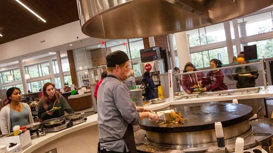 Students watch a chef prepare food at TWU's new dining hall