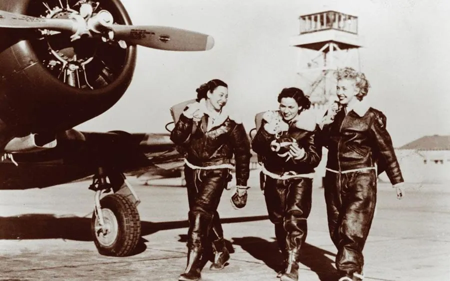 WASP archive photo of three female pilots in uniform walking down a tarmac