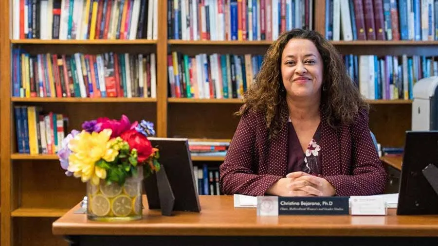 Christina Bejerano seated at a desk with bookshelves behind her