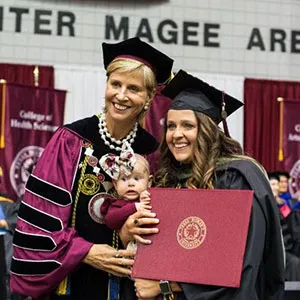 Chancellor Feyten at Spring 2019 commencement ceremony with graduate and baby