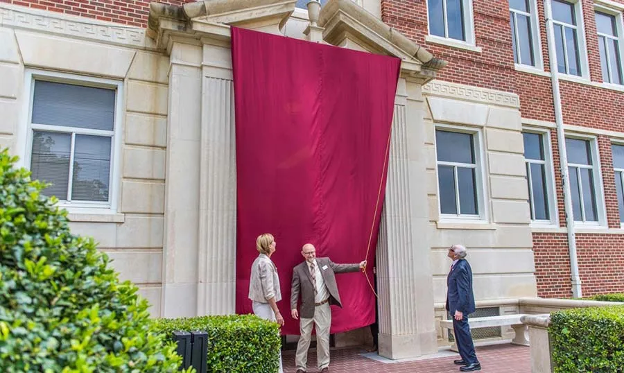 Chancellor Feyten and Dr. Daniel Miller unveil the renamed Woodcock Hall in May 2018