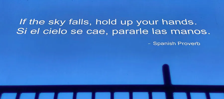 Text reads 'If the sky falls, hold up your hands' then repeats the phrase in Spanish