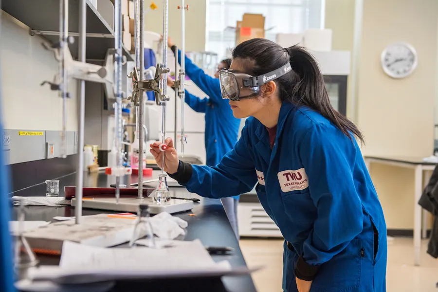 A TWU chemistry student carefully measures liquid into a beaker