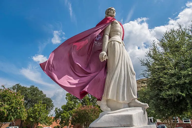 statute of Minerva with a maroon cape on a sunny day 