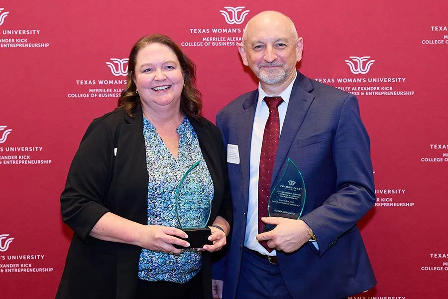Shelia Hyde stands next to David Rylander with award in front of TWU backdrop