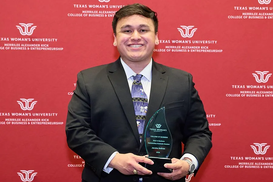 Jacobe Beltran holds a glass plaque in front of a maroon backdrop