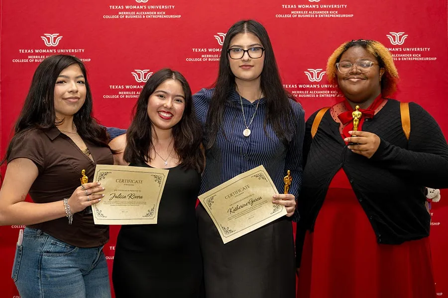 Katherine Garcia stands with three other MAK College students in front of TWU backdrop