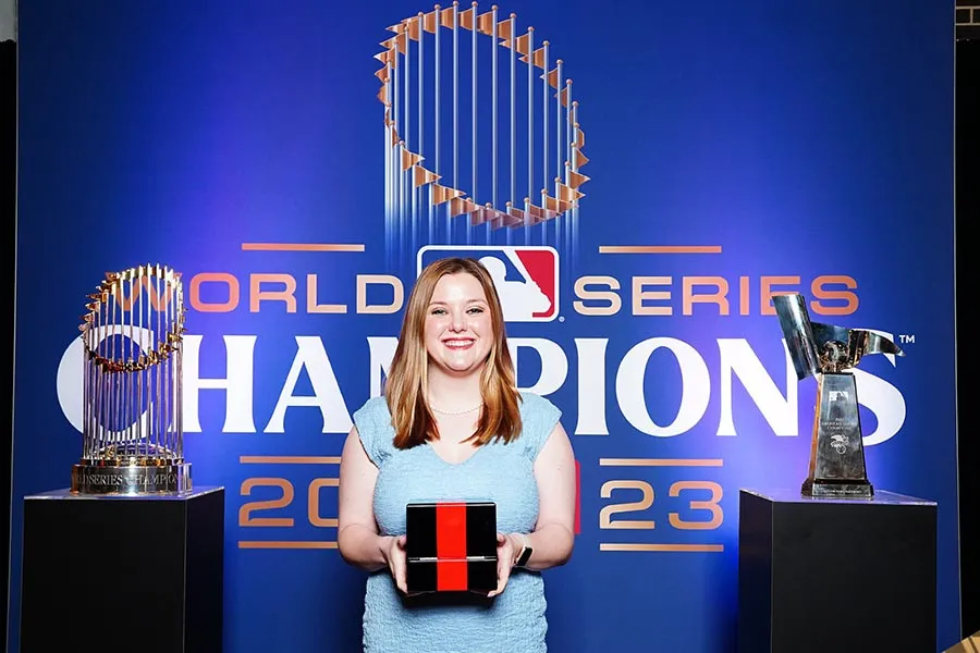 TWU alum Jesse Malone holds World Series ring box in front of blue World Series backdrop