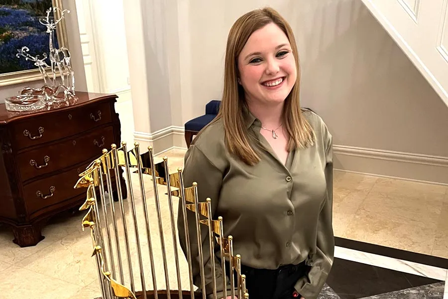 ̽¥ alum Jesse Malone stands next to a World Series Trophy in a foyer
