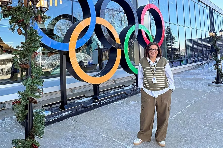 Vanessa Miranda stands in front of large Olympic rings on the front of NBC Sports office