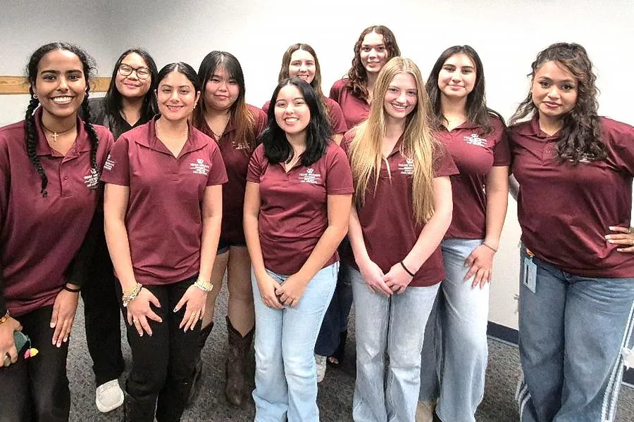 10 female students stand in 2 rows wearing maroon polos