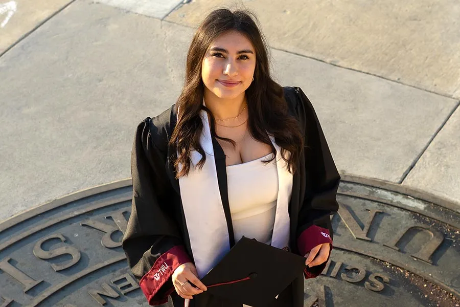 Romina-Vargas-Trujillo in graduation attire standing on the ̽��¥ seal