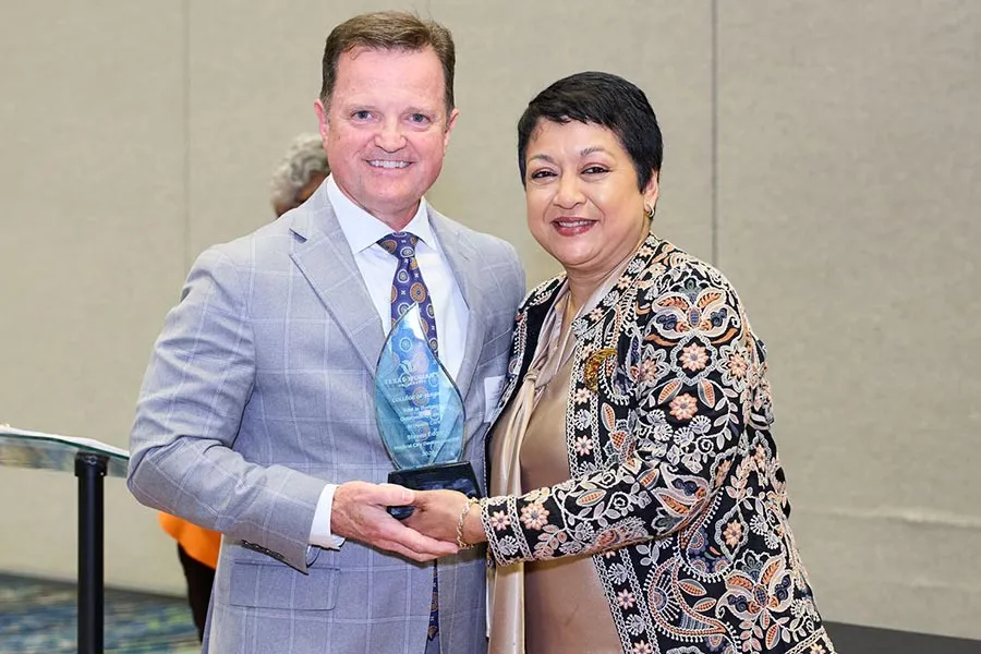 Steven Edgar stands with Dean Yelkur holding a glass plaque