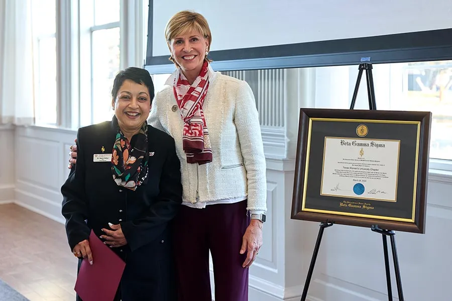 Dean Yelkur stands next to Chancellor Feyten next to an easel with Beta Gamma Sigma certificate
