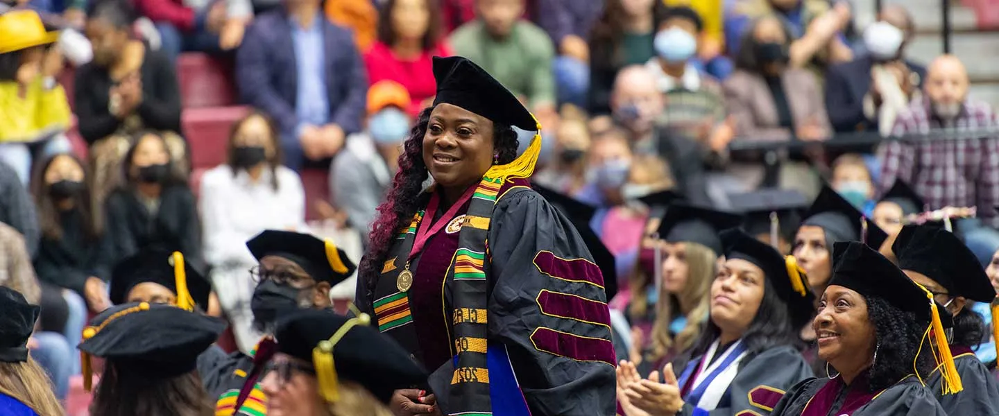 A TWU graduate stands during a Denton commencement ceremony.