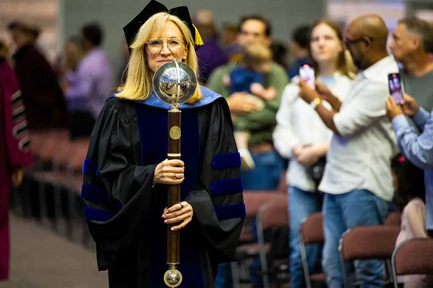 TWU's Provost, Dr. Bauer, holds The Mace of the University during the commencement procession.