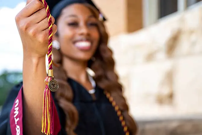A TWU graduate holds her Senior Giving Challenge cord up with pride.