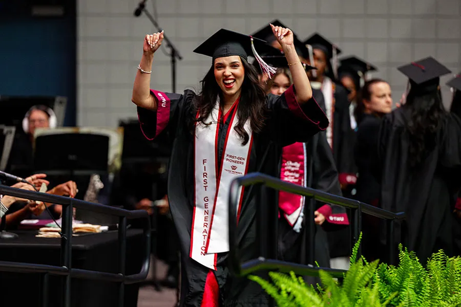 A Dallas graduate pumps her fists in victory as she walks the stage