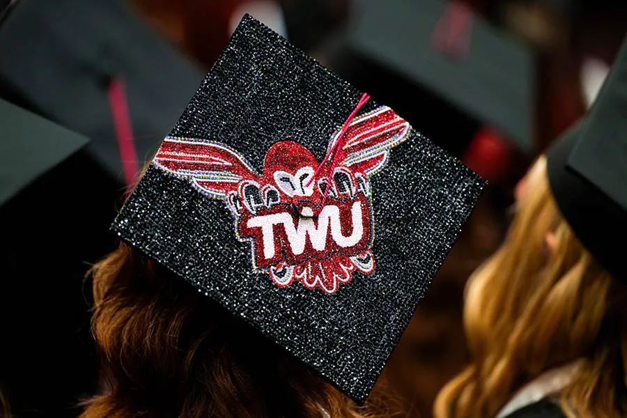 A close-up of a graduation cap with the TWU Athletics logo done in rhinestones