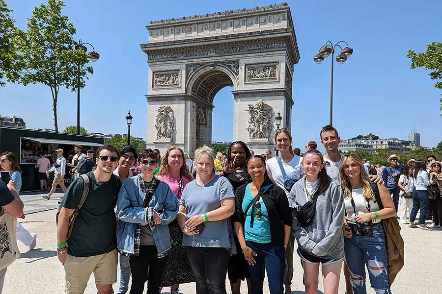 a group of students stand in front of the Arc de Triophe on a sunny day