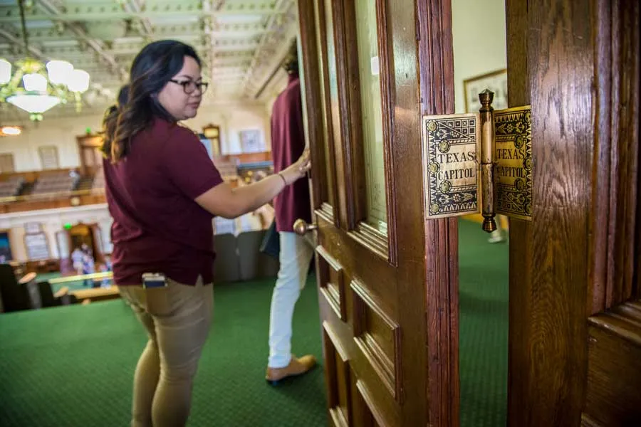 A TWU student opens the door to the Texas Capitol building.