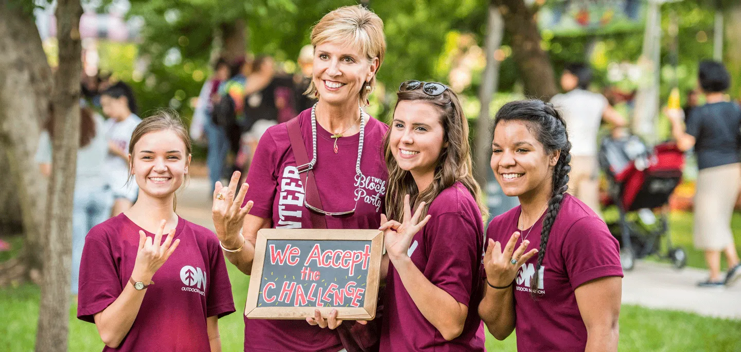 Chancellor Feyten poses with three TWU students at a Denton event.