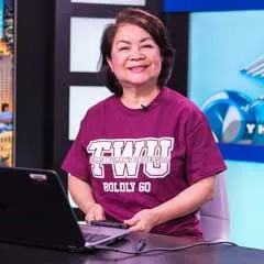 Tuong-Vi Ho sits on a TV news set.
