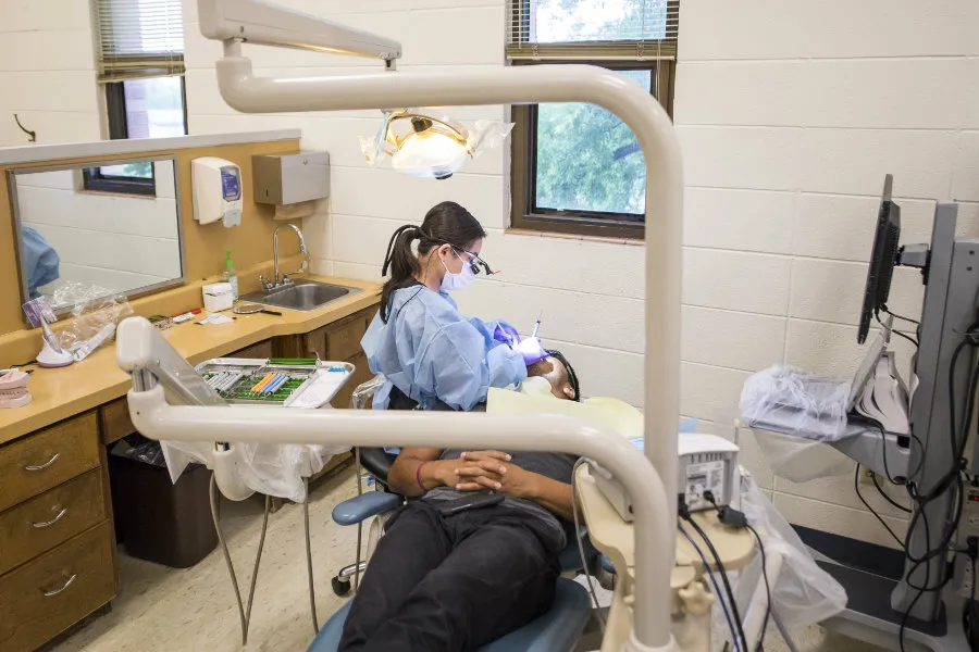 A TWU Dental Hygiene students works on a patients teeth in a dentists office setting. 