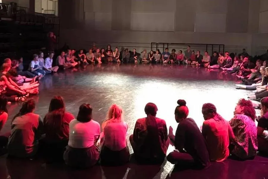 Dancers sit in a circle discussing improvisation