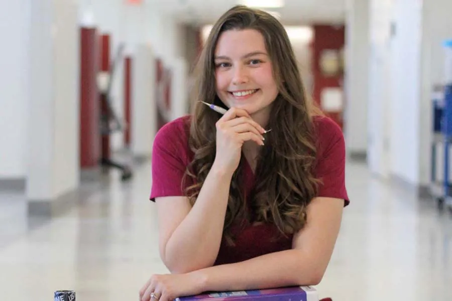 a èƵ dental hygiene student in maroon scrubs holds a syringe in her hand