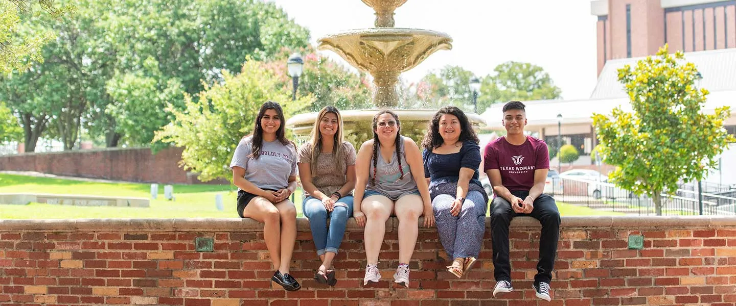 Students relax at the fountain on the Denton campus