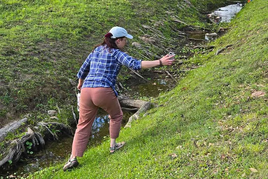 A young woman takes photos of local wildlife at a water source