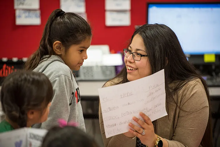 A TWU student teacher works with a young girl in the classroom