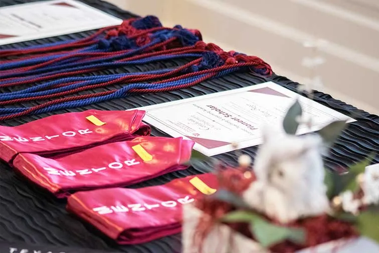 maroon stoles, certificates, cords laying on a table