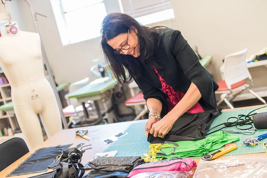 A young woman works at a large sewing table pinning a pattern together