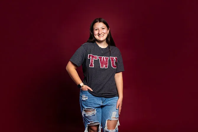 A smiling TWU student portrait on a maroon background and dressed casually.