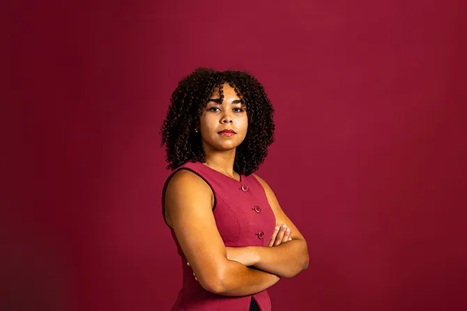 A determined looking TWU student portrait on a maroon background and dressed professionally.