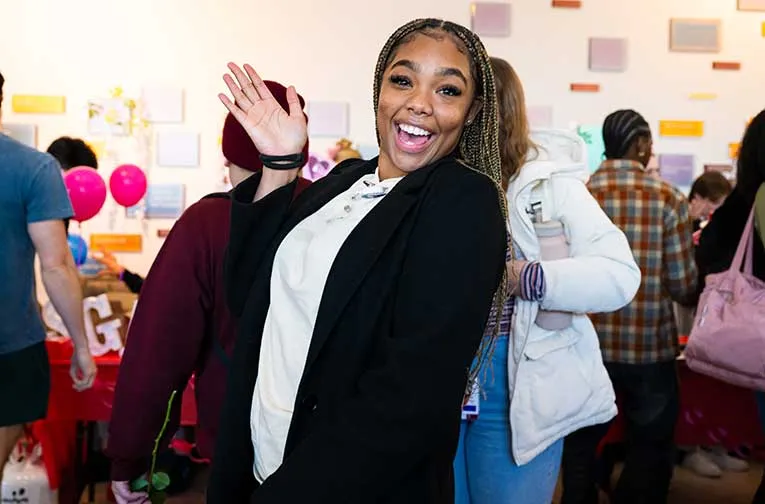 A TWU student in business attire at an event in the Dallas campus lobby.