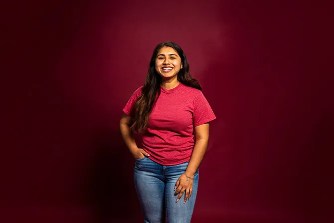 A smiling TWU student portrait on a maroon background and dressed casually.