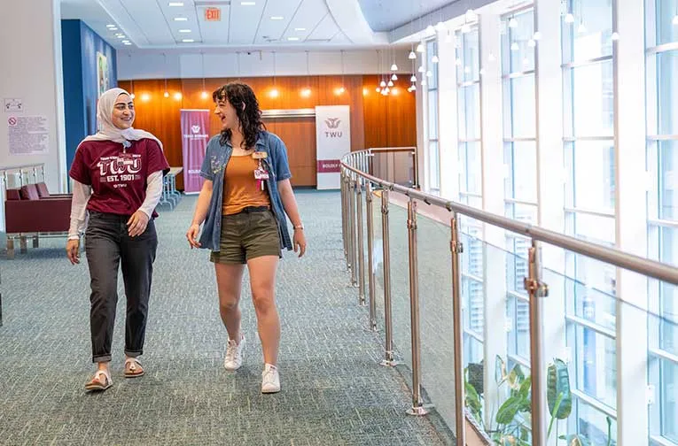 Two TWU students walk through the TWU Houston campus building.
