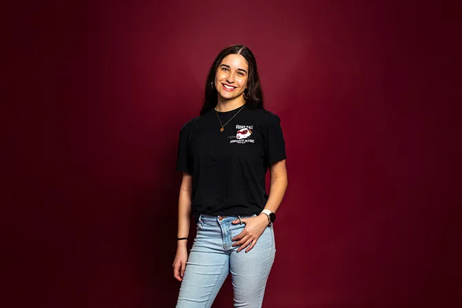 A smiling TWU student portrait on a maroon background and dressed casually.