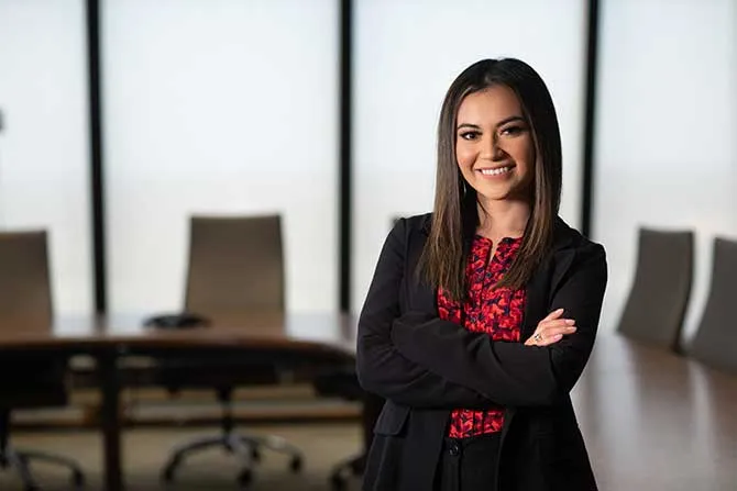 A TWU MBA student stands in a board room setting in professional attire.