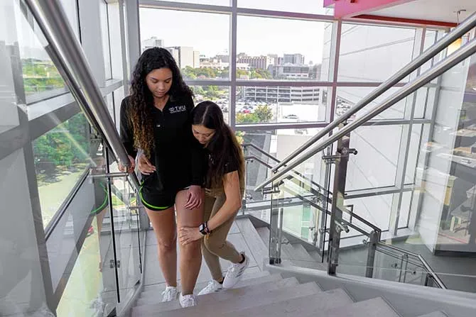 A TWU PT student assists another student going up the stairs in a PT demonstration on the Dallas campus.