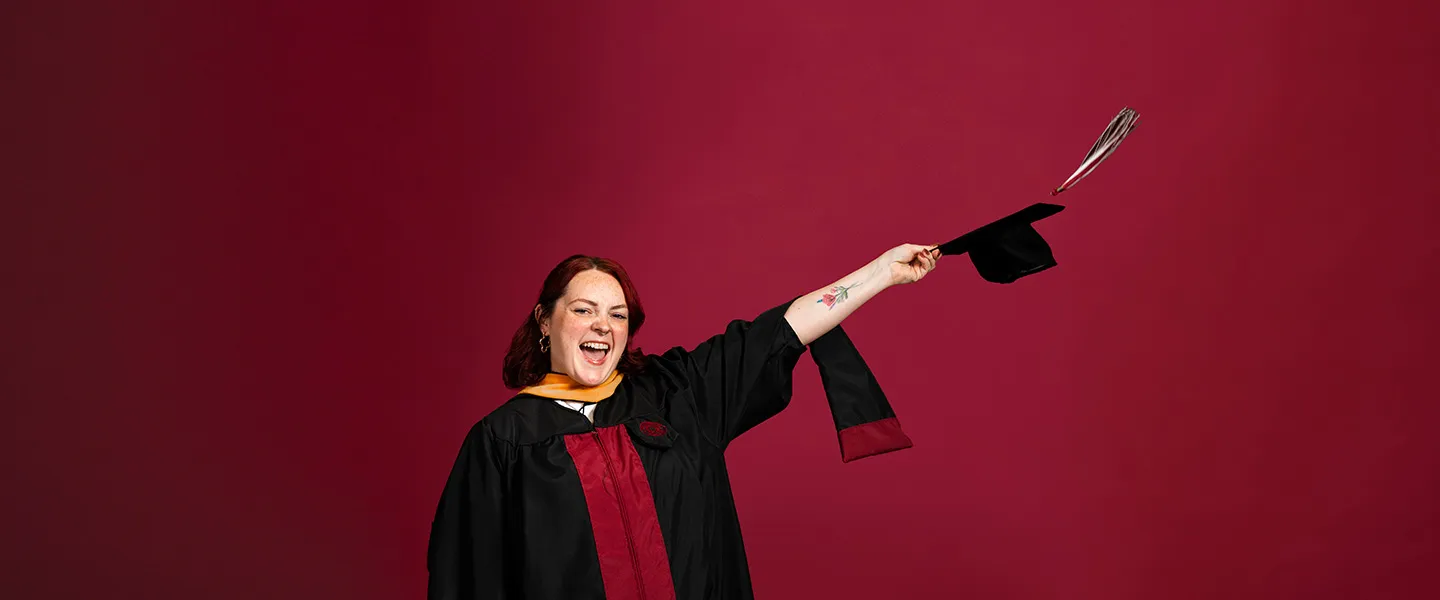 A portrait of a TWU graduate student in adacemic regalia on a maroon background.