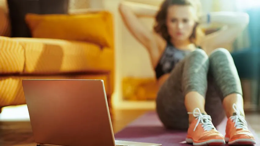 Woman doing crunches while looking at a laptop 