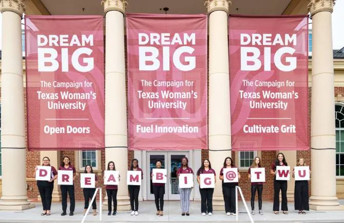 Students holding signs with letters that spell 