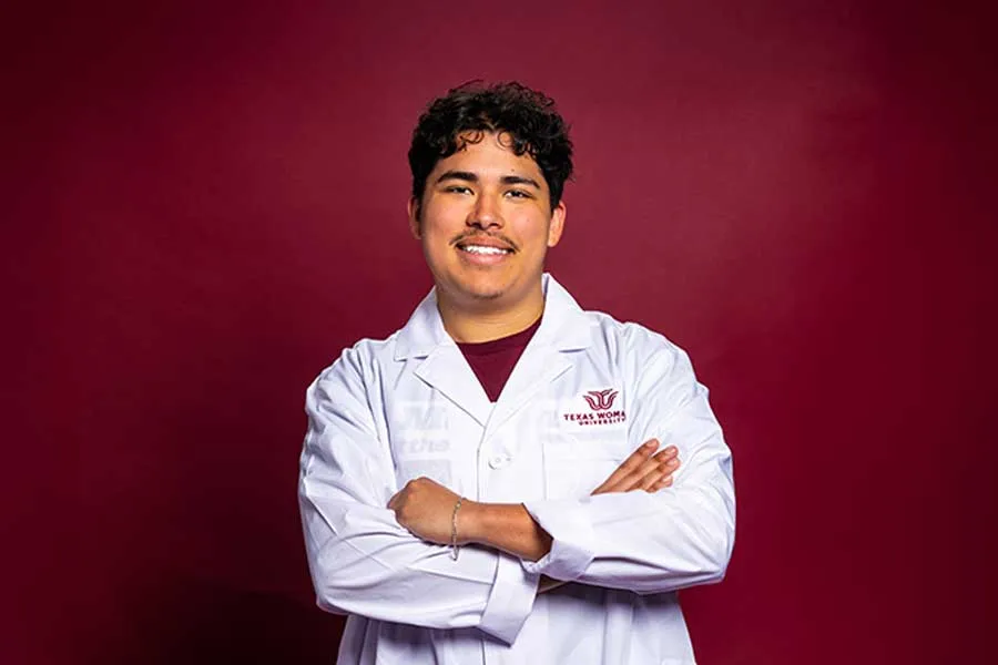 A dramatic portrait of a TWU student in a science lab white coat.